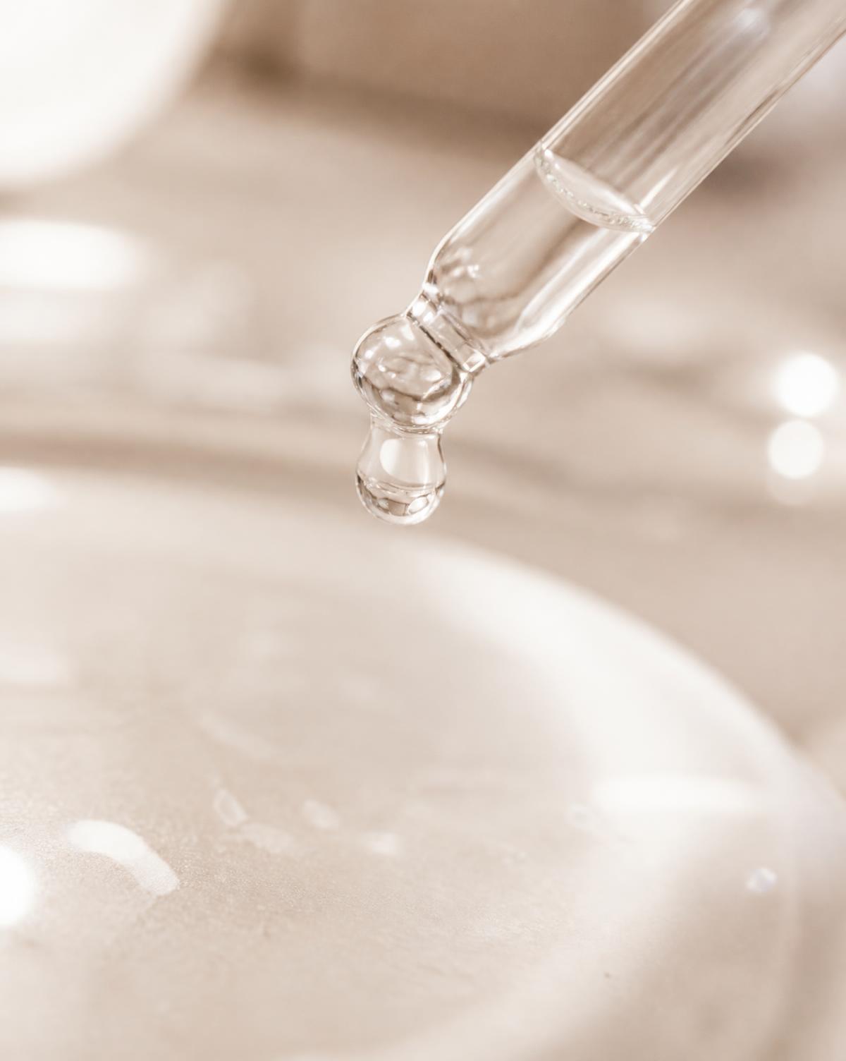 Macro detail of a serum pipette releasing a single drop